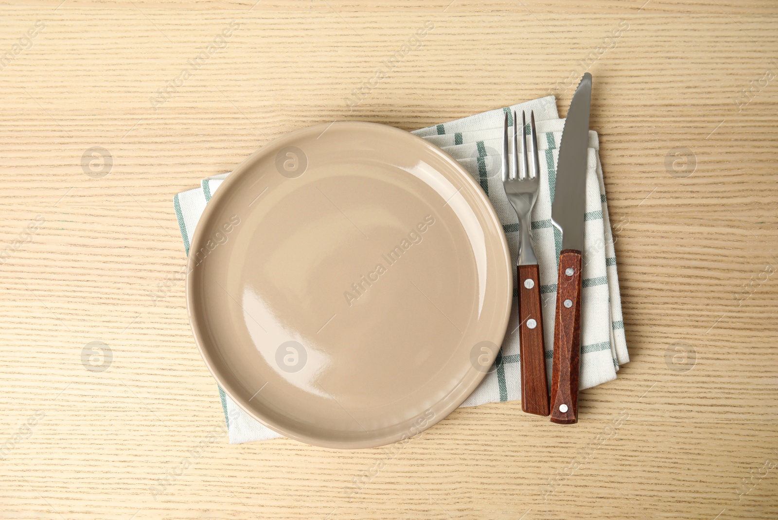 Photo of Empty plate, cutlery and napkin on wooden table, flat lay