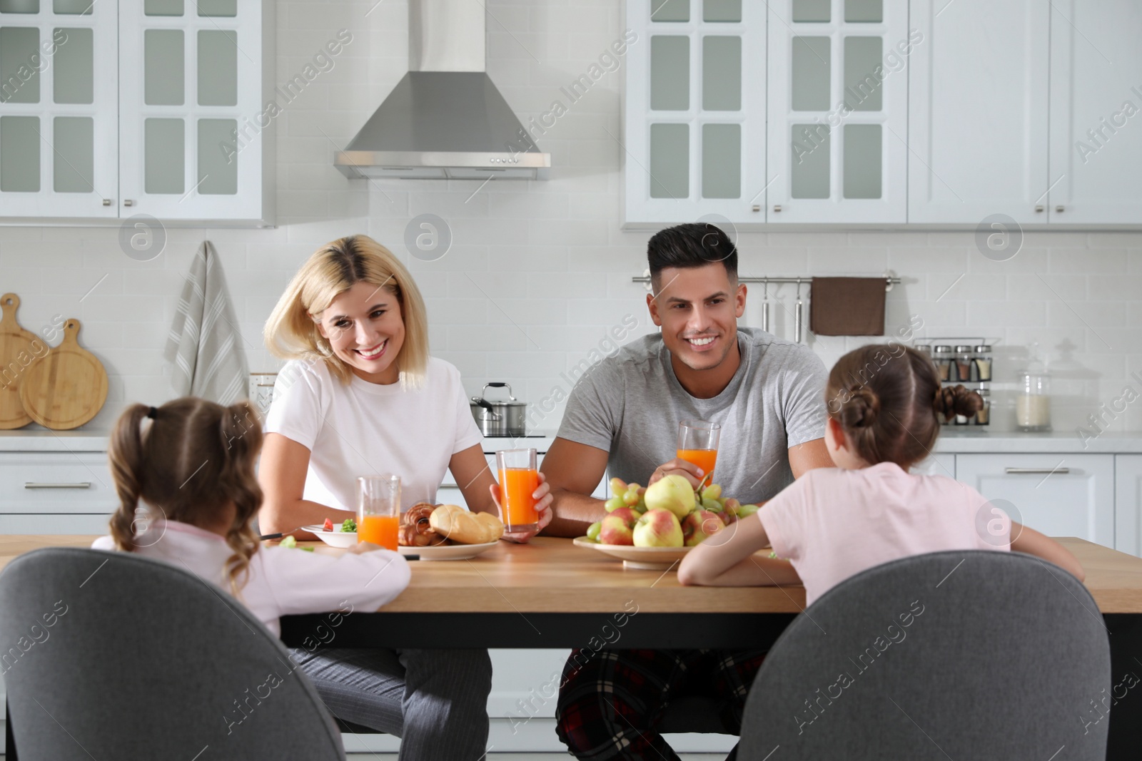 Photo of Happy family having breakfast together at table in modern kitchen