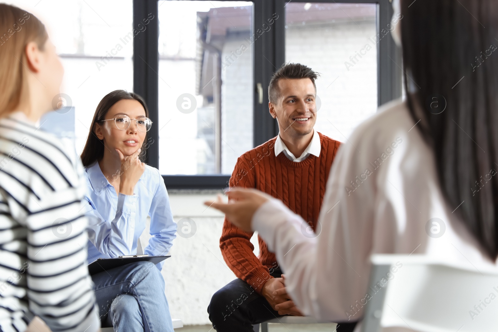 Photo of Psychotherapist working with patients in group therapy session indoors