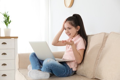 Photo of Little girl using video chat on laptop at home