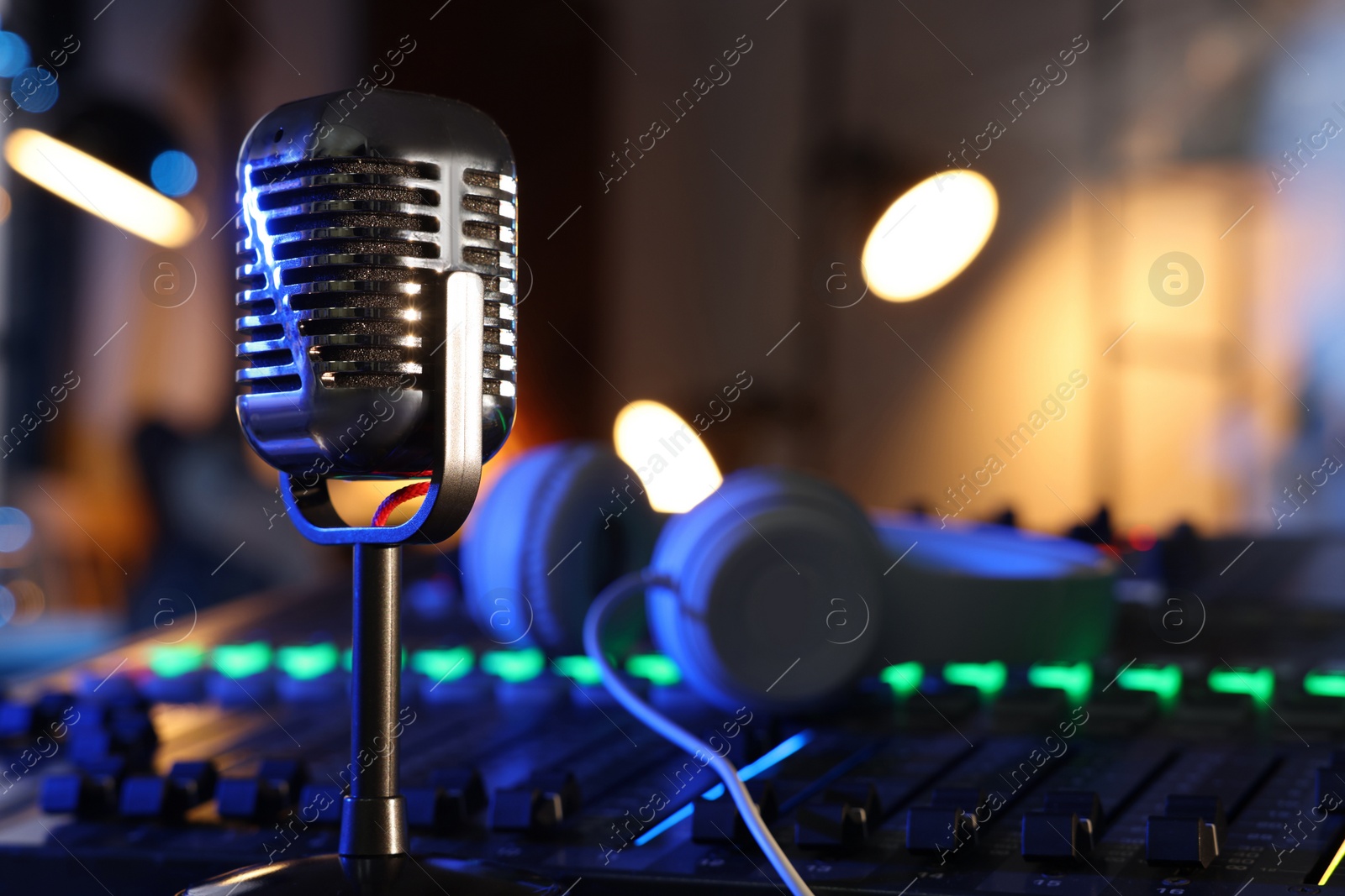 Photo of Microphone near professional mixing console and headphones in radio studio