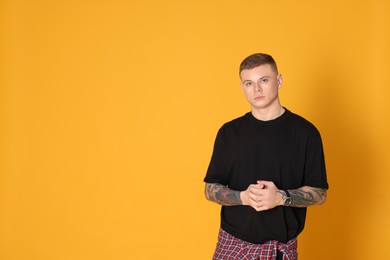 Young man with tattoos on yellow background. Space for text