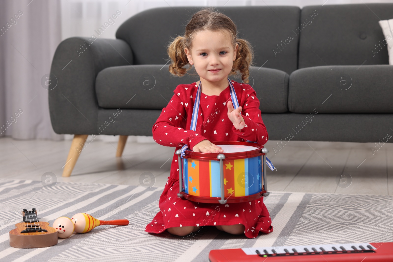 Photo of Little girl playing toy drum at home