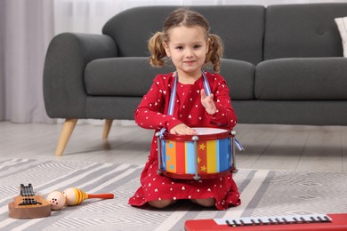 Little girl playing toy drum at home