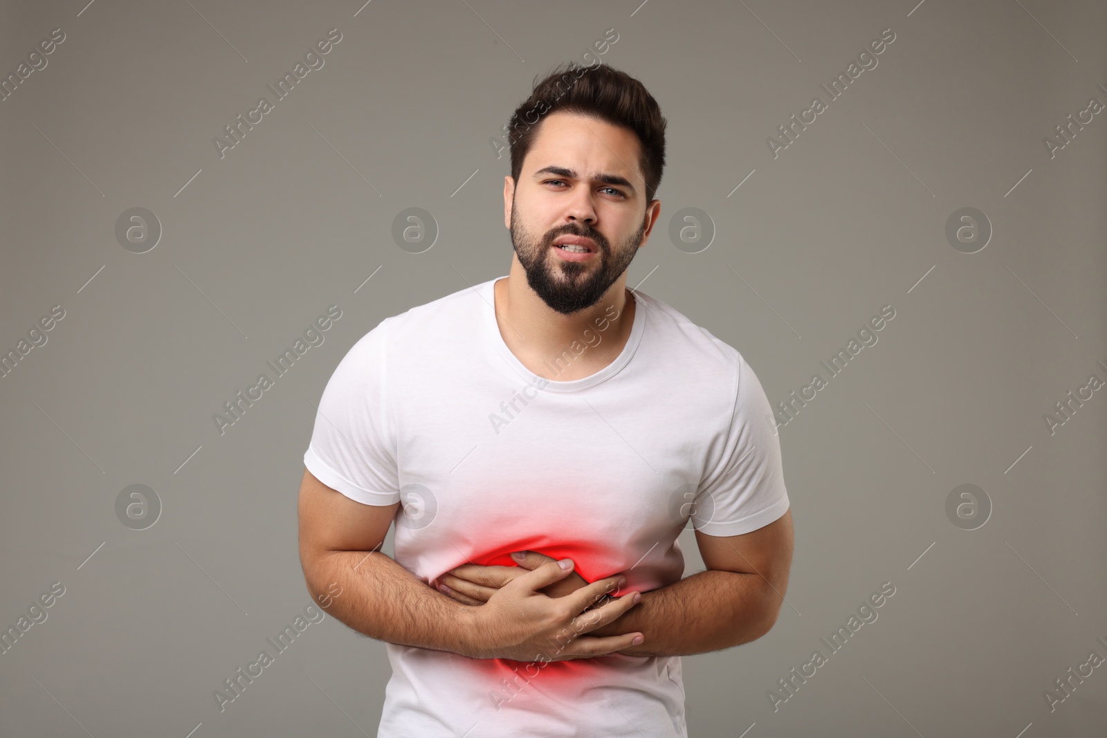 Image of Man suffering from abdominal pain on grey background