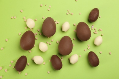 Photo of Sweet chocolate eggs on light green background, flat lay