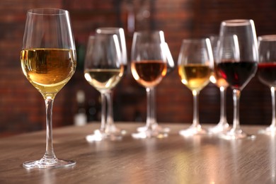 Different tasty wines in glasses on wooden table