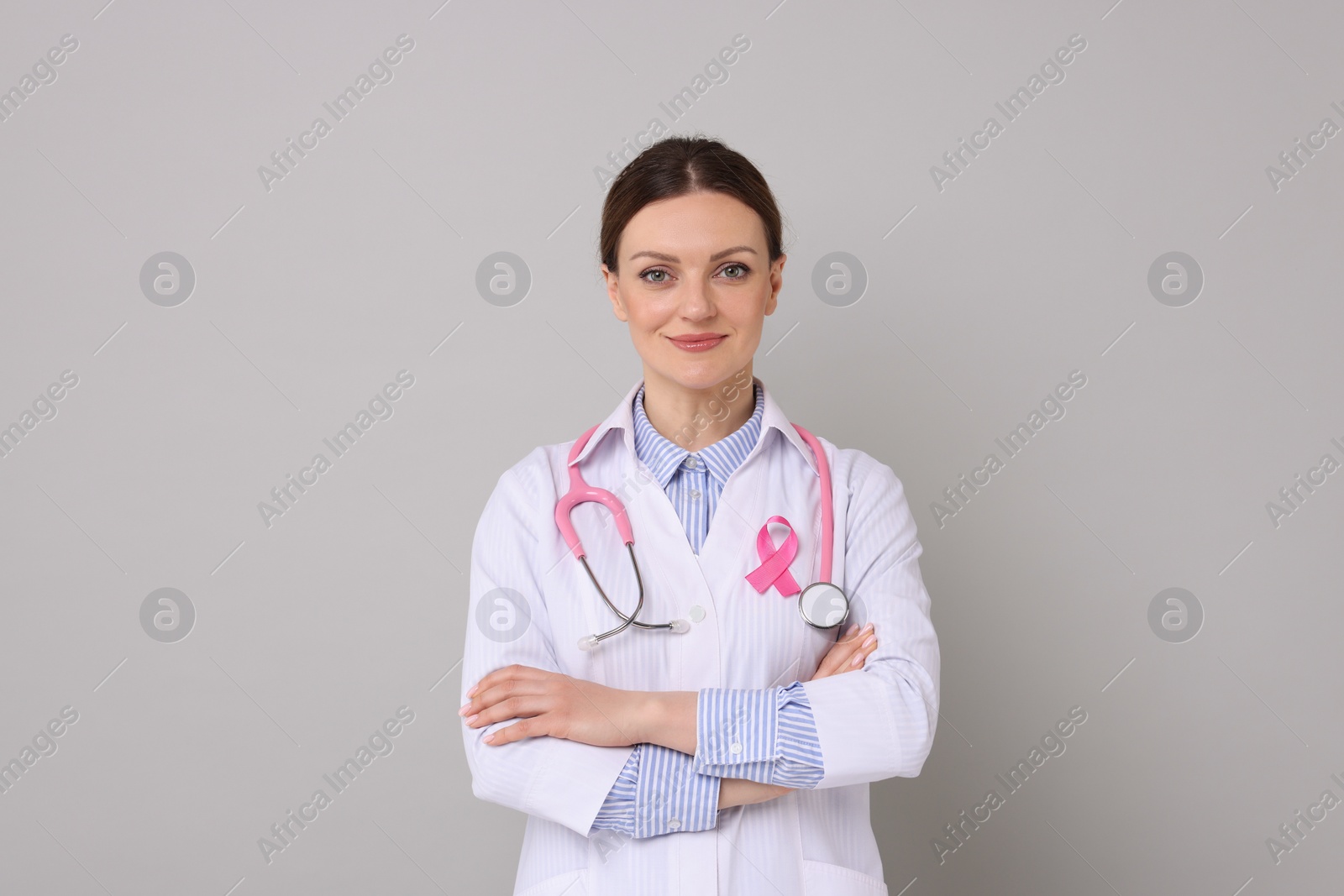 Photo of Mammologist with pink ribbon on grey background. Breast cancer awareness