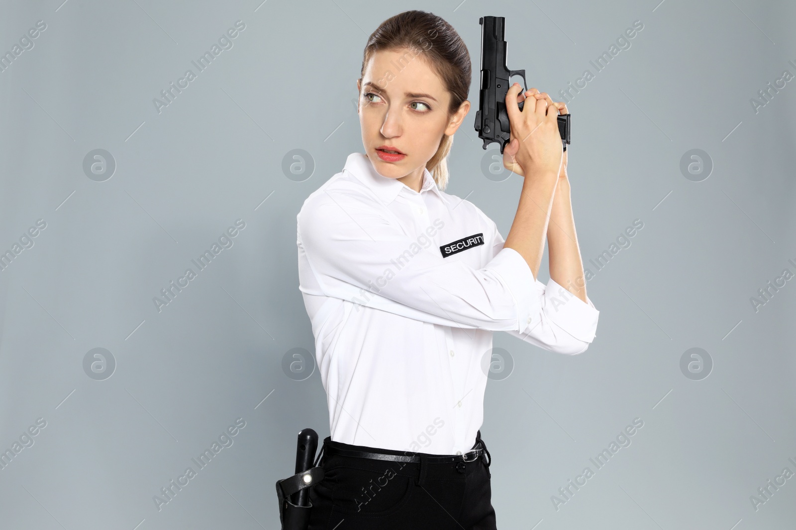 Photo of Female security guard in uniform with gun on grey background