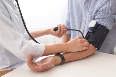 Doctor checking patient's blood pressure in hospital, closeup. Cardiology concept