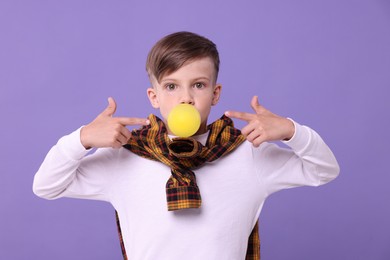 Surprised boy blowing bubble gum on purple background
