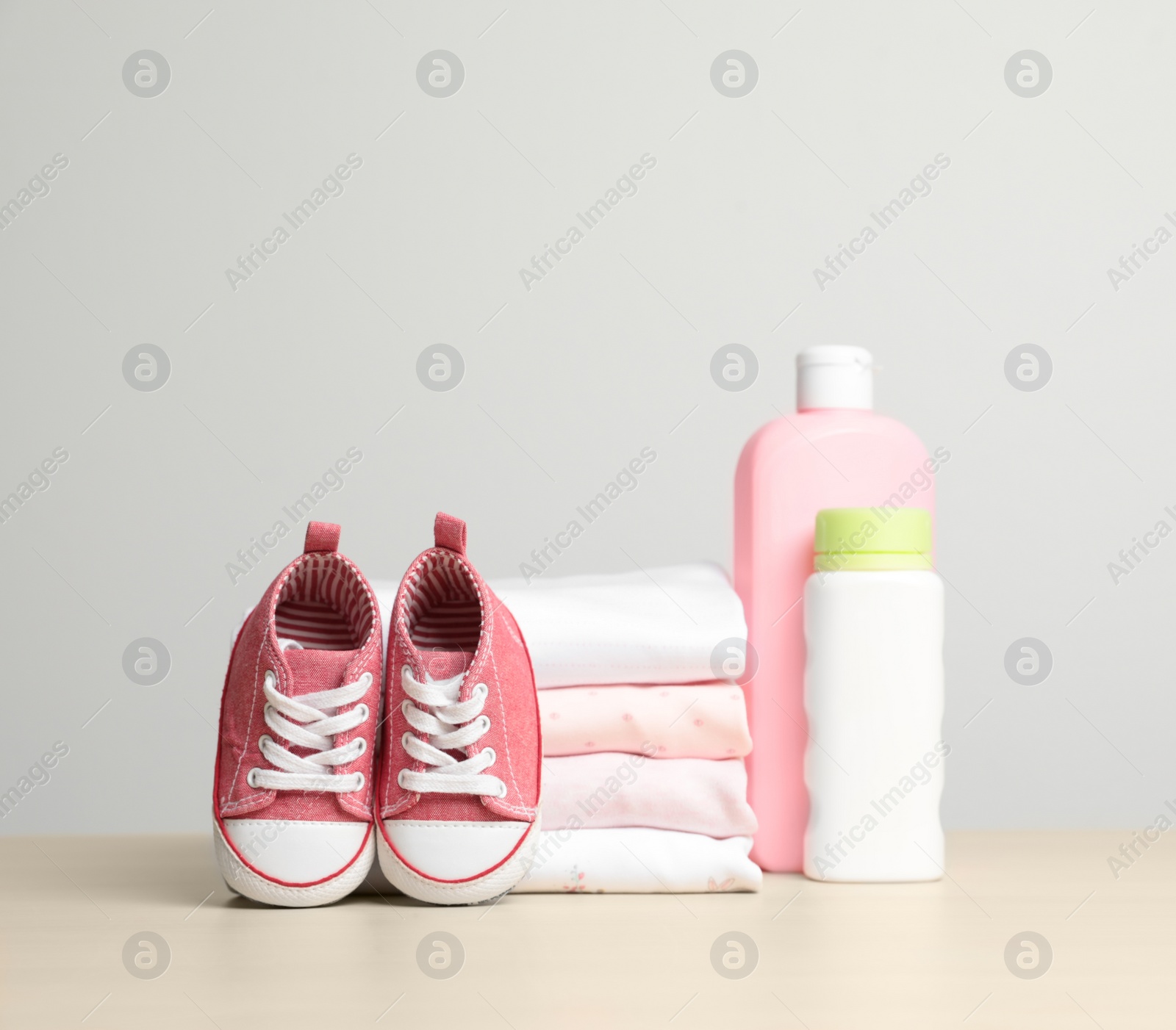 Photo of Baby clothes, booties and accessories on wooden table