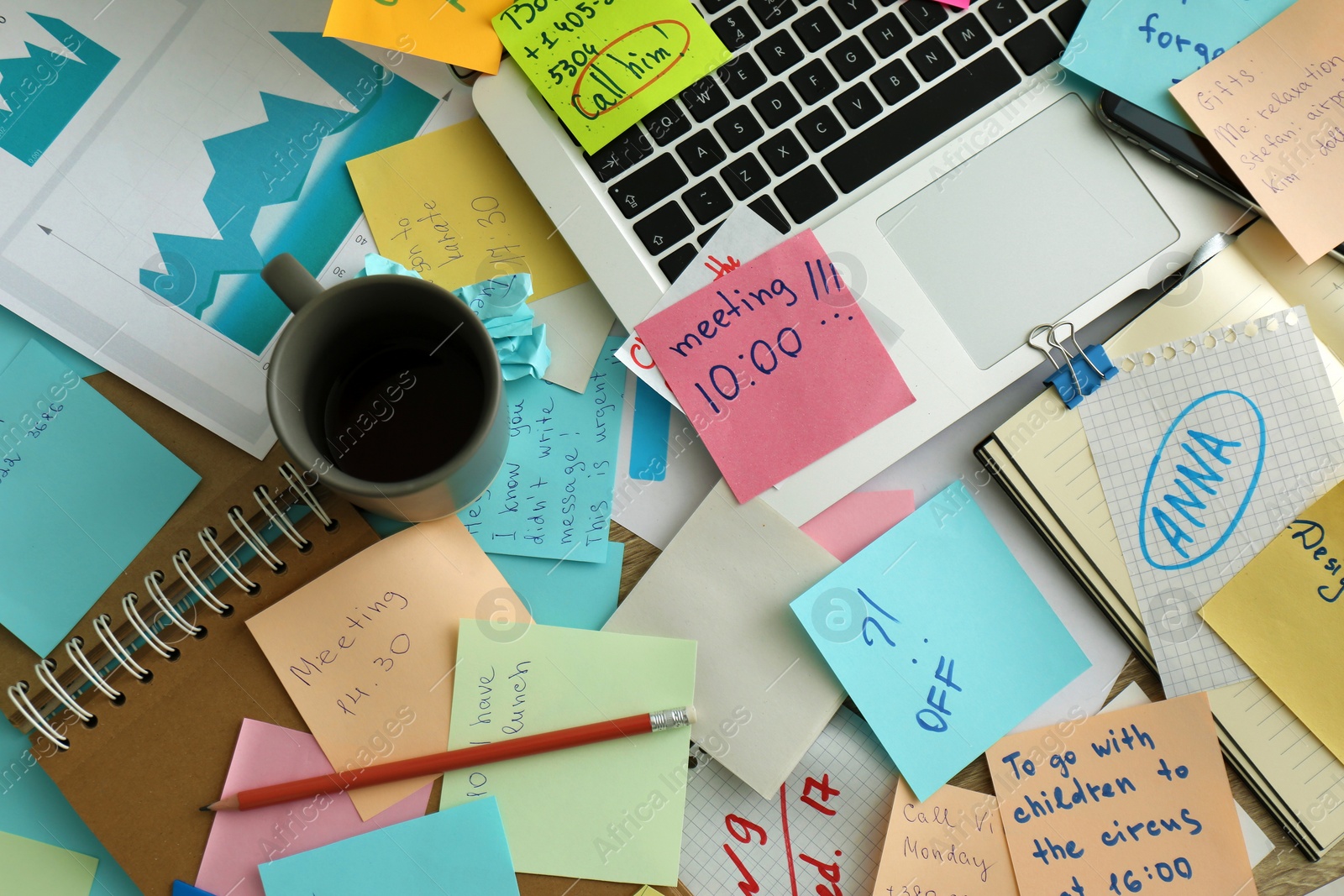 Photo of Laptop, notes and office stationery in mess on desk, top view. Overwhelmed with work