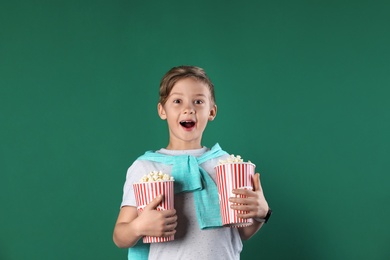 Cute boy with popcorn buckets on color background