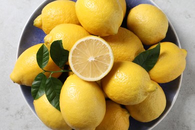 Photo of Fresh lemons and green leaves on light table, top view