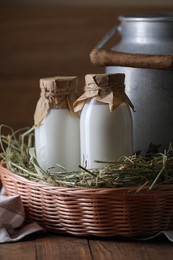 Photo of Tasty fresh milk in can and bottles on wooden table
