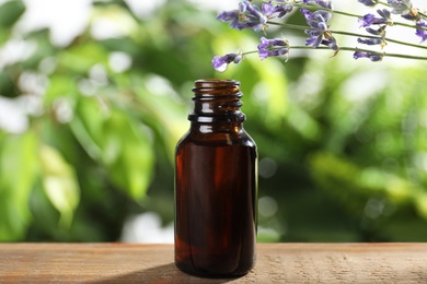 Bottle of lavender essential oil on wooden table against blurred background