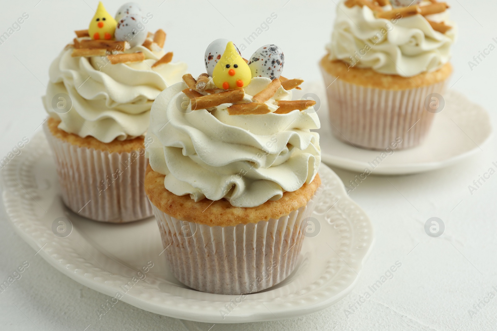 Photo of Tasty Easter cupcakes with vanilla cream on white table, closeup