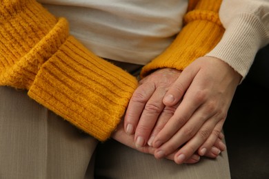 Young and elderly women holding hands together, closeup