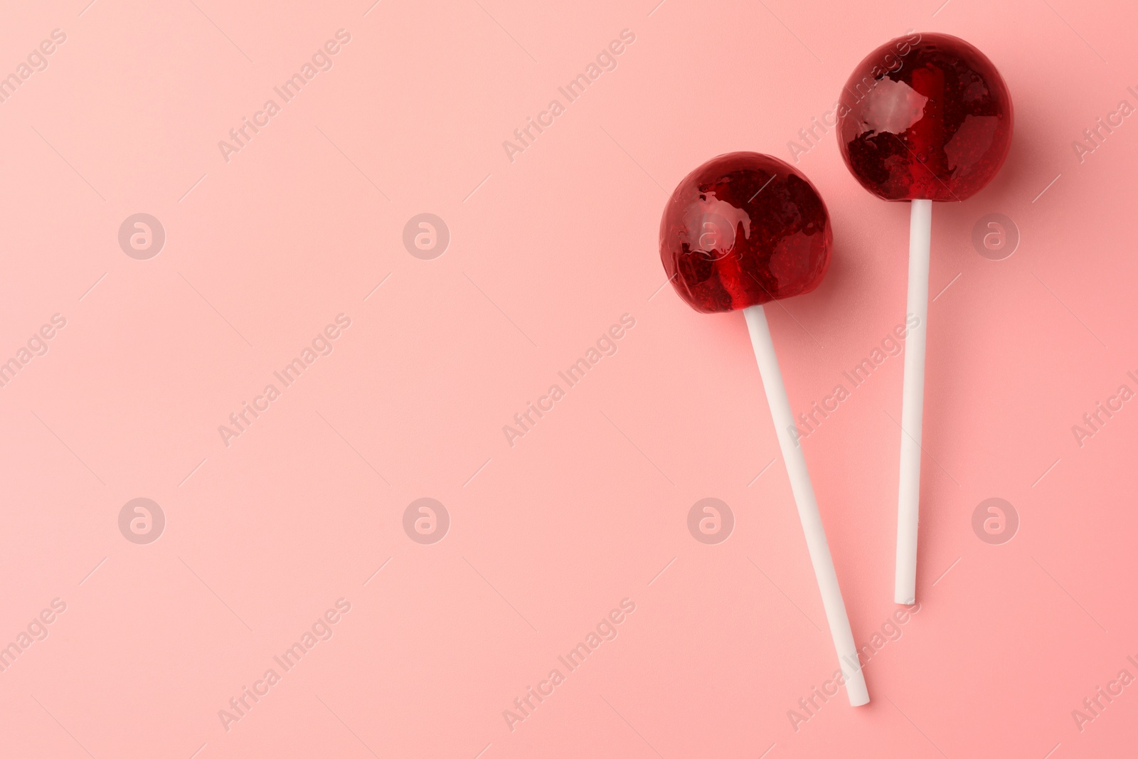 Photo of Tasty lollipops on pink background, flat lay. Space for text