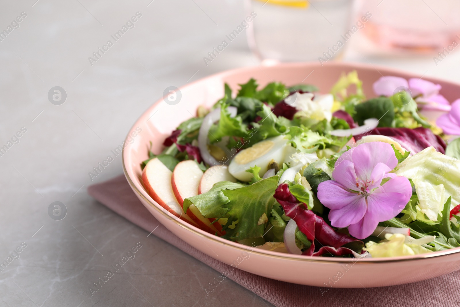 Photo of Fresh spring salad with flowers on grey table, closeup