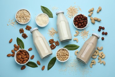 Different vegan milks and ingredients on light blue background, flat lay