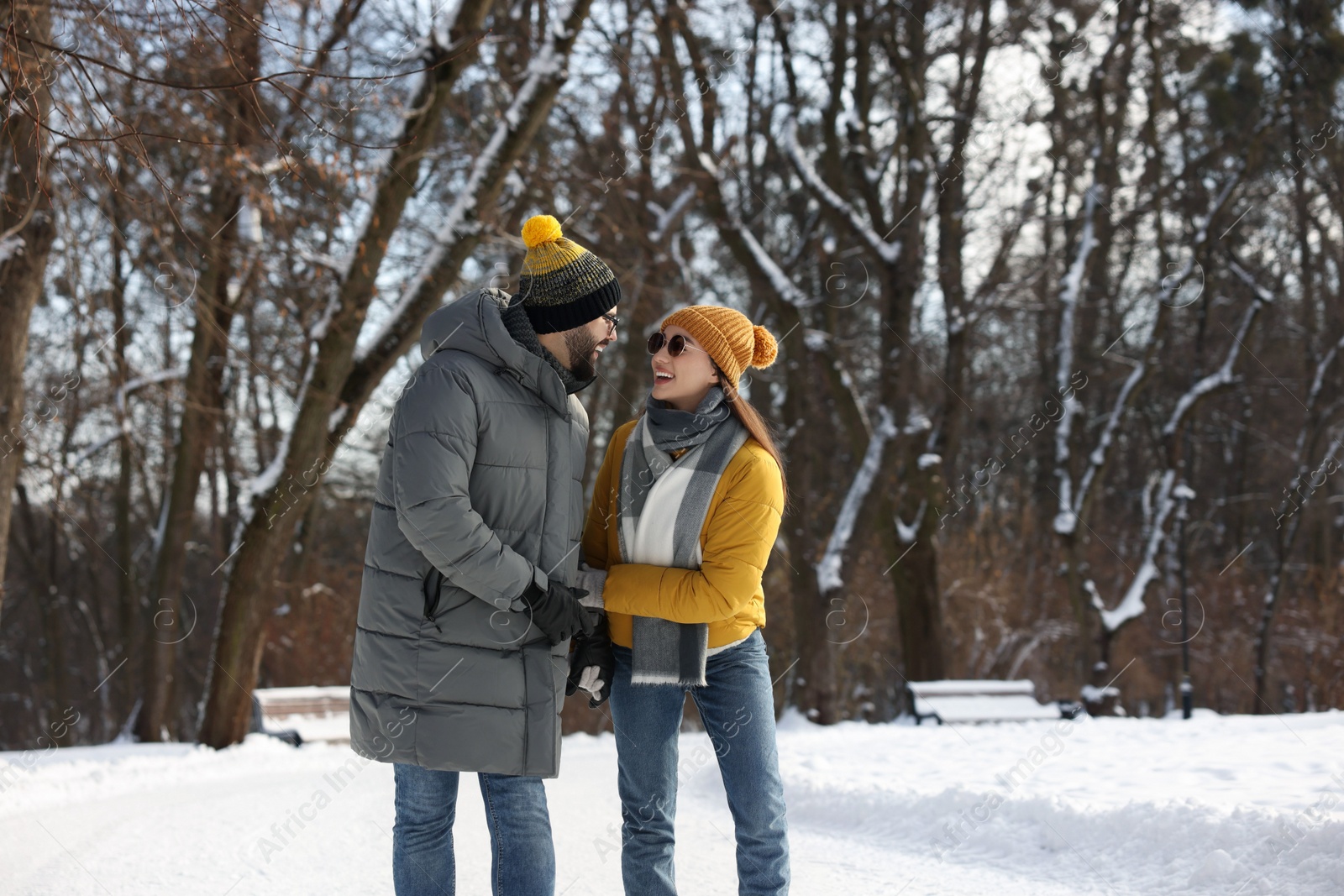 Photo of Beautiful happy couple walking in snowy park on winter day