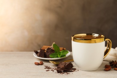 Photo of Yummy hot chocolate in cup on white wooden table, space for text