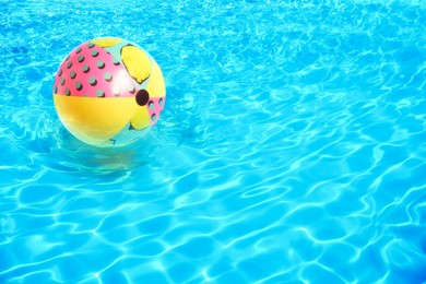 Image of Inflatable beach ball floating in swimming pool 
