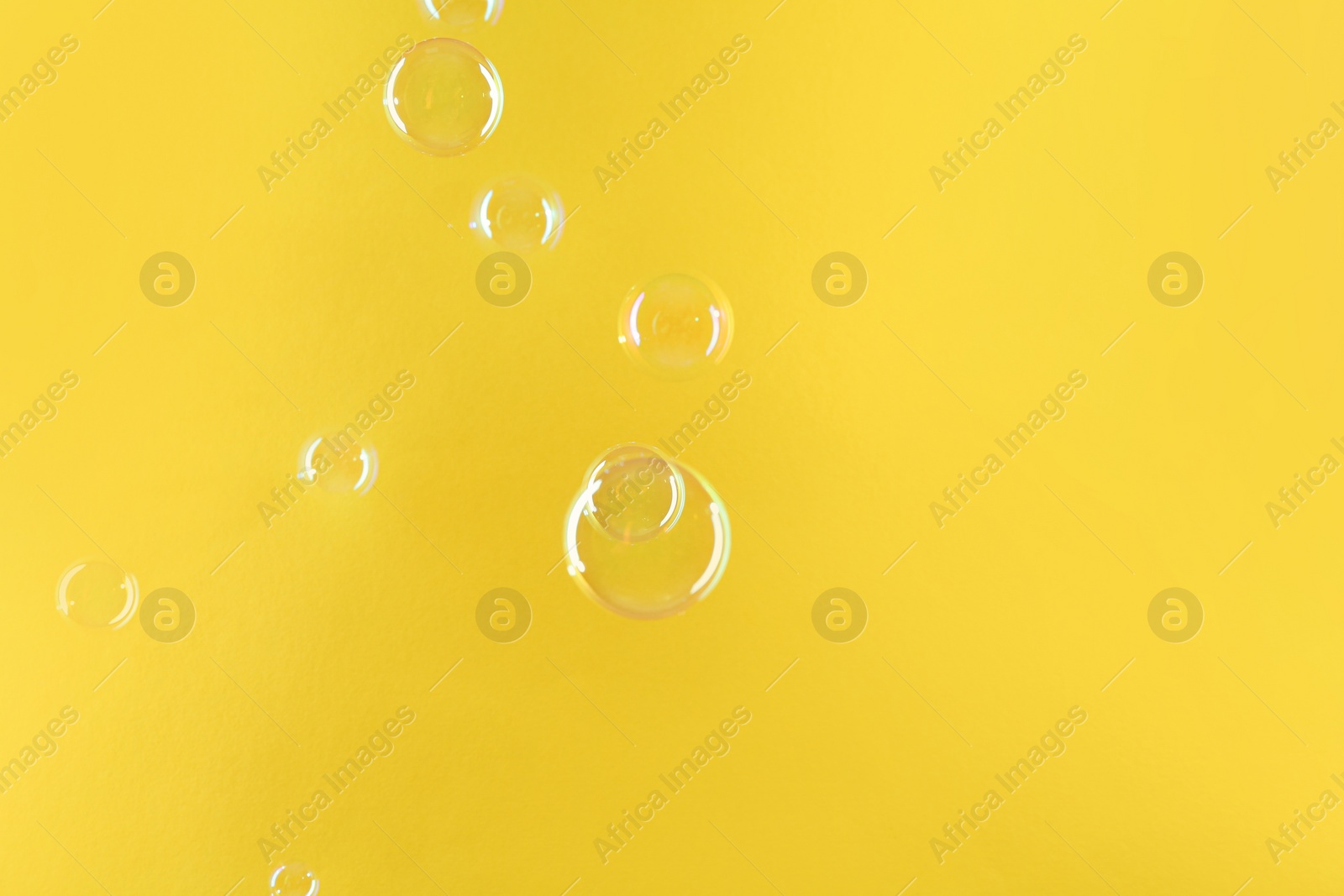 Photo of Beautiful transparent soap bubbles on yellow background, space for text