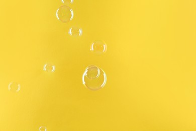 Photo of Beautiful transparent soap bubbles on yellow background, space for text