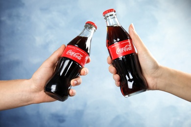 MYKOLAIV, UKRAINE - NOVEMBER 15, 2018: People with bottles of Coca Cola on color background, closeup