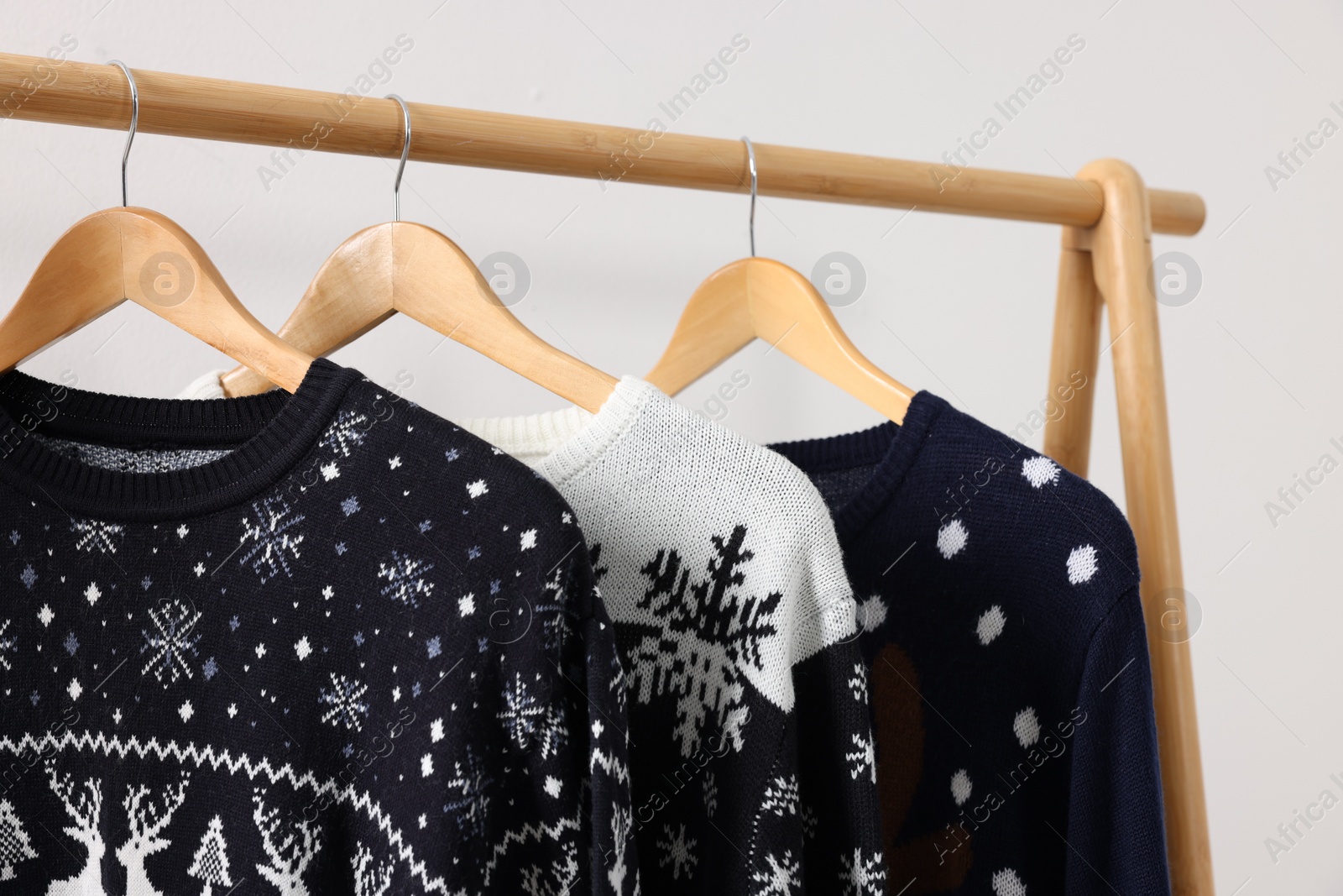 Photo of Rack with different Christmas sweaters on white background, closeup