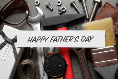 Photo of Card with phrase HAPPY FATHER'S DAY, different tools and male accessories on grey background, flat lay
