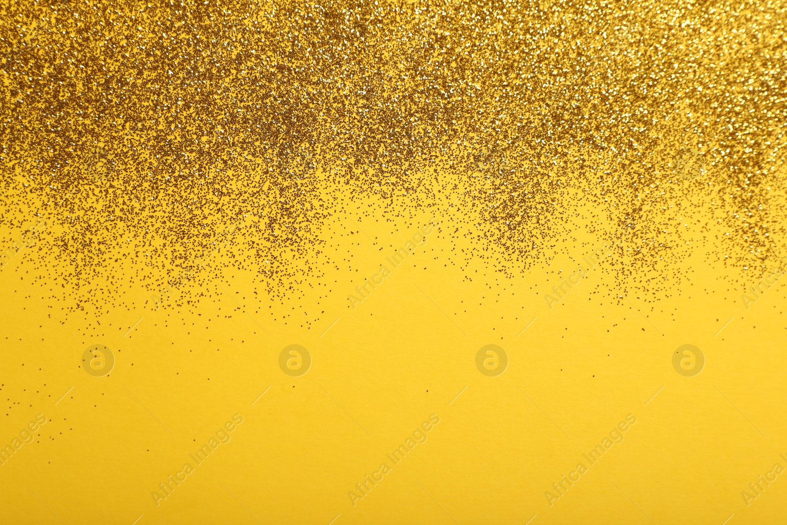 Photo of Shiny golden glitter on yellow background, top view. Space for text