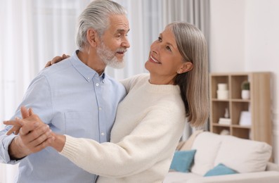 Happy affectionate senior couple dancing at home