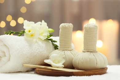 Photo of Beautiful composition with different spa products and flowers on white towel against blurred background, closeup