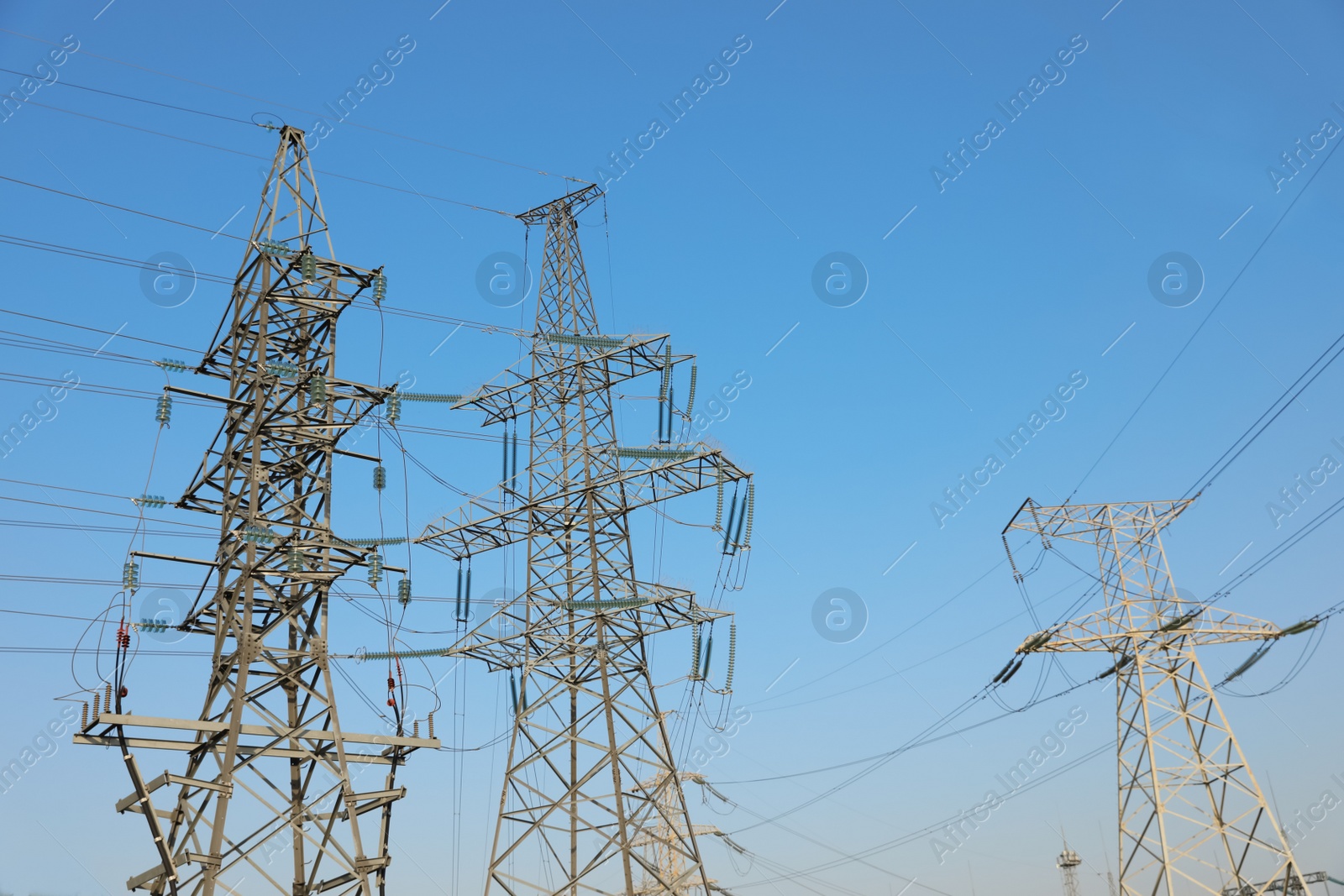 Photo of High voltage towers against blue sky on sunny day