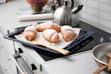 Photo of Baking tray with tasty croissants on stove
