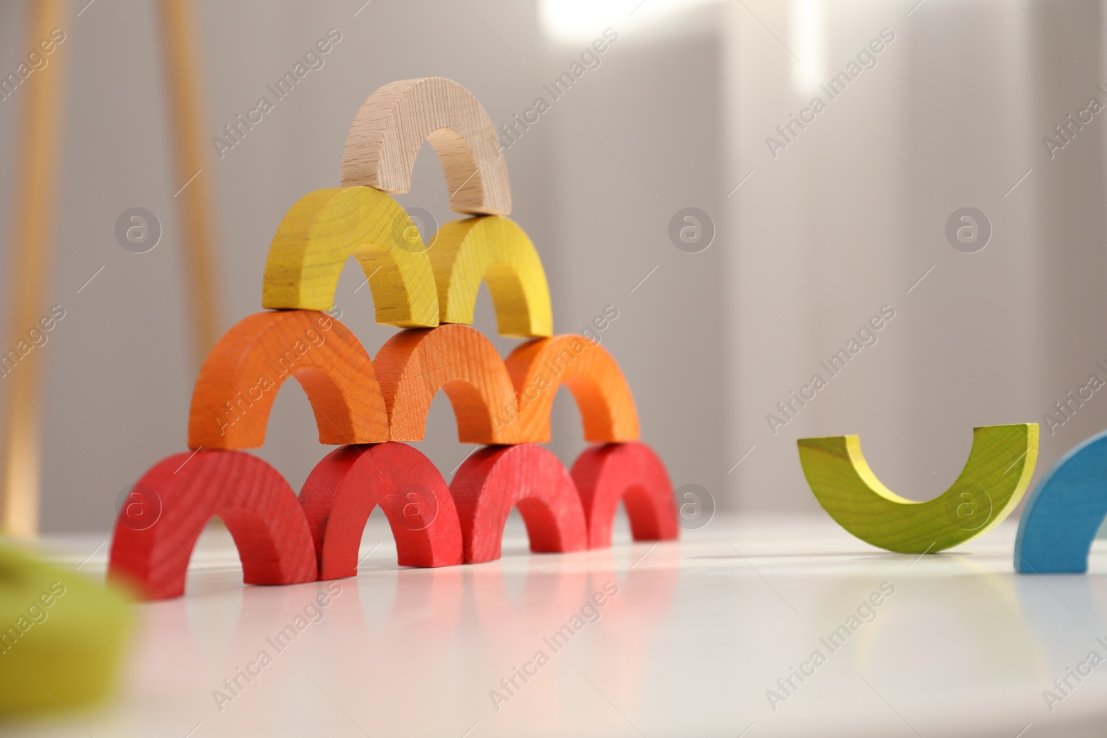 Photo of Colorful wooden pieces of play set on white table indoors. Educational toy for motor skills development