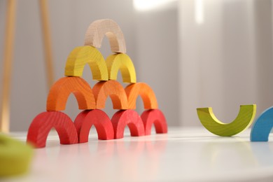 Photo of Colorful wooden pieces of play set on white table indoors. Educational toy for motor skills development