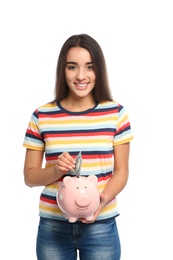 Photo of Portrait of young woman putting money into piggy bank on white background