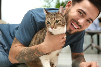 Photo of Happy man with cat on floor at home. Friendly pet