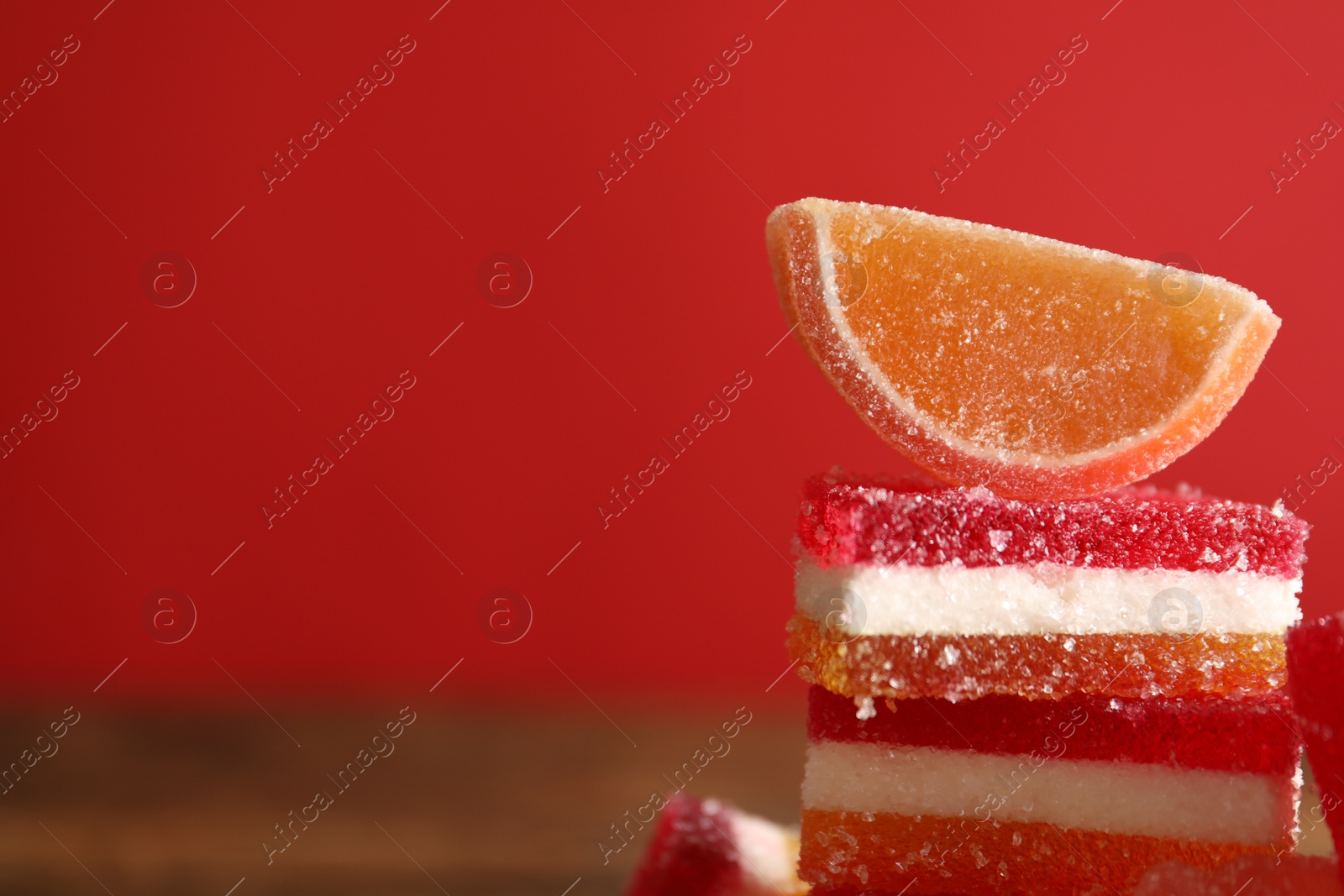 Photo of Delicious jelly candies on red background, closeup. Space for text
