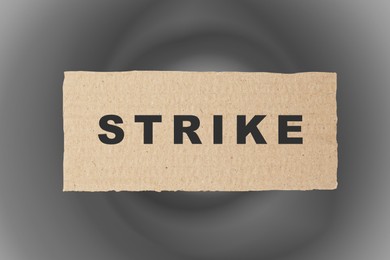 Image of Piece of cardboard with word Strike on abstract grey background