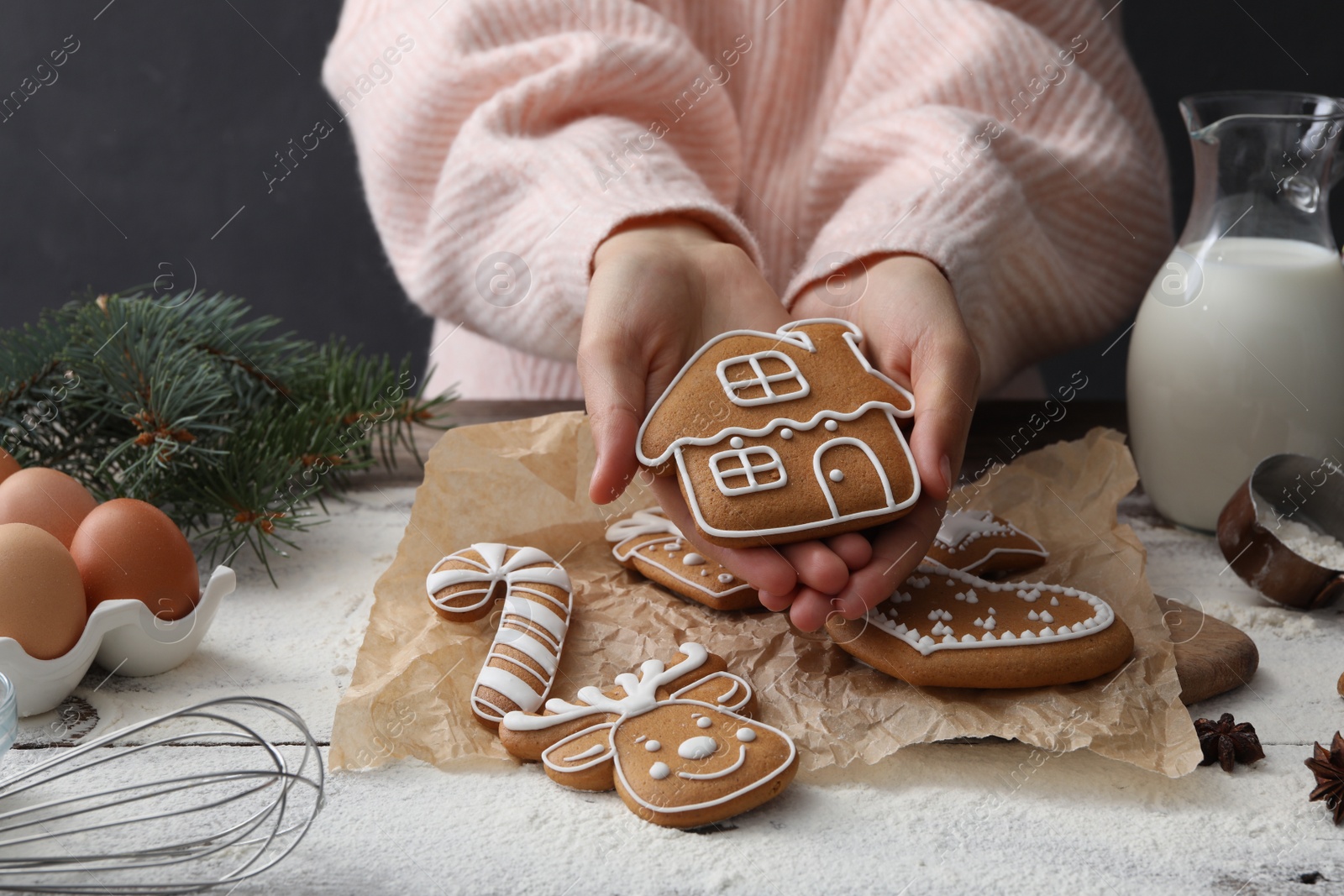 Photo of Woman holding delicious homemade Christmas cookie at wooden table, closeup