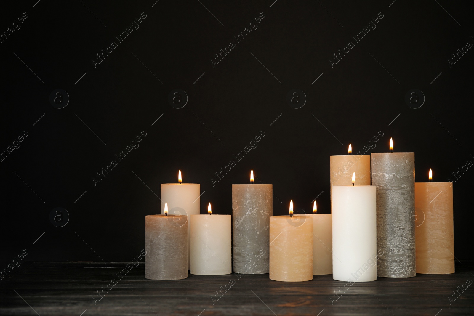 Photo of Alight wax candles on table against dark background. Space for text