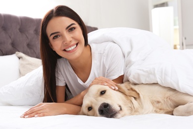 Photo of Young woman and her Golden Retriever dog on bed at home