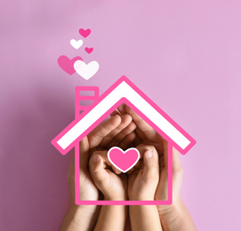 Mother holding hands with child and illustration of house on pink background, top view.  Adoption concept