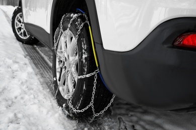 Photo of Car with snow chain on tire, closeup. Winter season